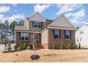 Two-story home featuring a brick facade and siding, set on a manicured lawn with mature trees at 40 Ironwood Blvd, Youngsville, NC 27596