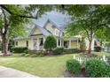 Inviting two-story home with a charming front porch, beautiful landscaping, and mature trees at 4001 Falls River Ave, Raleigh, NC 27614
