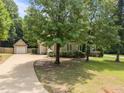 View of the home and detached garage, highlighted by a long driveway and mature trees at 44 Supreme Dr, Lillington, NC 27546