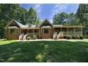 Backyard view of the brick home with a lush lawn and a covered porch at 5464 Bass Mountain Rd, Snow Camp, NC 27349