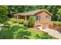 Brick home featuring an attached garage, a well-manicured lawn and lush landscaping at 712 Orange High School Rd, Hillsborough, NC 27278