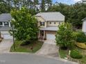Aerial view of a two-story home nestled in a tree-filled neighborhood with well-manicured lawns and a paved driveway at 1040 Bellenden Dr, Durham, NC 27713