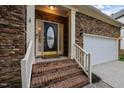 Close-up of a home's front door with decorative glass, brick steps, and a two-car garage to the right at 1040 Bellenden Dr, Durham, NC 27713