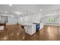 Modern kitchen island with white marble countertop and seating, complemented by hardwood floors and unique light fixtures at 3516 Swift Dr, Raleigh, NC 27606