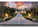 Stately home with a long driveway, lush landscaping, and exterior lamp posts illuminating the property at 387 Riverstone Dr, Pittsboro, NC 27312