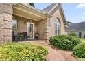 Charming front porch with brick support columns, red flowers, and a beautifully patterned walkway at 412 Whitt Ave, Burlington, NC 27215