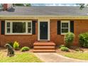 Inviting brick home entrance with blue door, black shutters, and manicured landscaping at 4703 Pleasant Green Rd, Durham, NC 27705