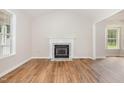 Spacious living room with hardwood floors, a cozy fireplace, and large windows providing ample natural light at 5428 Passenger Pl, Raleigh, NC 27603