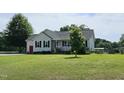 Charming home with well-kept lawn features a welcoming front porch, black shutters, and mature shade tree in the front yard at 56 Sugarhill Dr, Zebulon, NC 27597