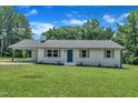 Charming single-story home with white brick, a teal door, shutters, a covered carport, and a lush green lawn at 802 Creech Church Rd, Kenly, NC 27542