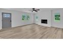 Bright living room with wood-look flooring, lots of windows, ceiling fan and a painted brick fireplace at 802 Creech Church Rd, Kenly, NC 27542