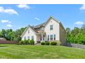 Beautiful home boasts lush green lawn, mature trees, and a classic facade under a sunny sky at 1154 Yorkshire Dr, Burlington, NC 27215