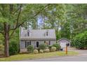 View of a well-maintained home, detached garage, and driveway amid mature trees at 1302 Valley Run Dr, Durham, NC 27707