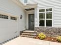 Attached garage with stone accents, front door, and stone steps at 132 Cotten Dr, Morrisville, NC 27560