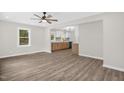 Open-concept living room with kitchen view, hardwood floors, ceiling fan, and natural light at 1605 Nixon St, Durham, NC 27707