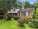 Charming home features a red front door, brick accents, mature landscaping, and lush green lawn at 204 Chatterson Dr, Raleigh, NC 27615