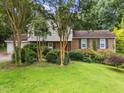 Home featuring brick accents, a red front door, shutters, and lush green landscaping at 204 Chatterson Dr, Raleigh, NC 27615