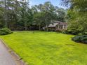 Expansive green lawn with mature trees surrounding a charming two-story home with traditional architecture at 204 Chatterson Dr, Raleigh, NC 27615