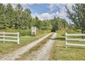 Long gravel driveway leading to Oxford Oaks property, framed by white fencing and lush greenery at 3679 Oak Lawn Farm Rd, Oxford, NC 27565