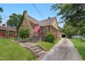 Charming brick home with a stone chimney, an American flag, and a long driveway at 407 Hillcrest Ave, Burlington, NC 27215