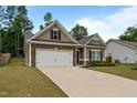 Low angle of a single-story home with stone accents and a two-car garage on a well-manicured lawn at 5081 Pioneer Dr, Sanford, NC 27330