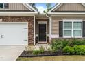 Close-up of the front door and landscaping including a two-car garage with stone accents at 5081 Pioneer Dr, Sanford, NC 27330
