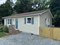 Corner view of a single-story home with a gravel driveway and newly constructed wooden fence at 510 North St, Graham, NC 27253