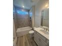 Modern bathroom with tiled shower-tub, granite countertop vanity, and hardwood floors at 85 Bald Cypress Ln, Youngsville, NC 27596