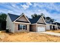 View of home shows neutral vinyl siding, brick accents, a two car garage, and landscaped yard at 1079 Fairhaven Dr # 50, Mebane, NC 27302