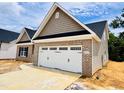 View of home shows neutral vinyl siding, brick accents, a two car garage, and landscaped yard at 1079 Fairhaven Dr # 50, Mebane, NC 27302