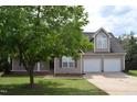 Charming home with a front porch and a two car garage, partially obscured by a tree at 136 Wedgewood Ct, Sanford, NC 27332