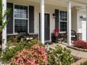 Inviting front porch with stone accents and outdoor seating surrounded by colorful flowers at 4179 Dunkirk Dr, Burlington, NC 27215