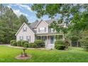 Charming two-story home with a cozy front porch, blue shutters, and meticulously landscaped front yard at 457 Poplar Forest Ln, Pittsboro, NC 27312