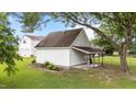Side exterior view of a detached white garage featuring a lean-to for storage and mature landscaping at 541 Mallie Pearce Rd, Zebulon, NC 27597