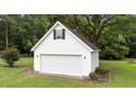 View of a detached two-car garage with white siding, black shutters, and well manicured lawn at 541 Mallie Pearce Rd, Zebulon, NC 27597