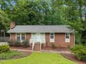 Inviting single-story brick home with a green lawn and landscaped garden area, perfect for outdoor enjoyment at 7916 Foxwood Dr, Raleigh, NC 27615