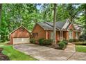 Brick home with attached garage and driveway, surrounded by mature trees and lush greenery at 101 Turnberry Ln, Cary, NC 27511
