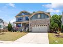 Charming two-story home with manicured lawn, stone accents, covered porch and a two car garage at 105 Blue Prince Trl, Holly Springs, NC 27540