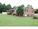 Brick ranch home featuring an expansive lawn, tidy landscaping, and classic architectural details at 1418 Sherron Rd, Durham, NC 27703