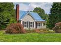 Charming single-Gathering home with a blue metal roof, brick chimney and a landscaped front yard at 4067 Williams Mill Rd, Burlington, NC 27215
