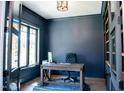 Stylish home office with dark blue walls, a wooden desk, and a large window offering plenty of natural light at 46 Lakes Edge Ln, Pittsboro, NC 27312