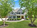 Beautifully landscaped home featuring a manicured lawn, circular driveway, gray siding, and an inviting front porch at 532 Joe Collins Rd, Lillington, NC 27546