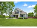Landscaped gray home featuring a sprawling lawn, elegant front porch, manicured landscaping, and circular driveway at 532 Joe Collins Rd, Lillington, NC 27546