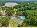 Aerial view of tennis courts, a community pool, and lush green landscaping near a lake at 6102 Burning Tree Cir, Sanford, NC 27332