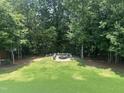A beautiful backyard featuring a circular paved fire pit surrounded by bench seating and mature trees at 7008 Rex, Holly Springs, NC 27540
