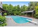 Gorgeous in-ground pool featuring a diving board and covered deck with seating, perfect for outdoor enjoyment at 7132 Deer Brook St, Willow Springs, NC 27592