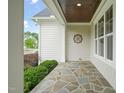 Inviting porch with stone flooring, white columns, and decorative ceiling at 121 Hardy Oaks Way, Holly Springs, NC 27540