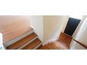 Entryway featuring hardwood steps with white trim, leading to a black front door at 5916 Longeria Ct, Raleigh, NC 27612