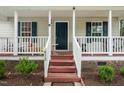 Charming front porch with a white railing, painted stairs, and dark shutters on the windows at 612 Agin Court Pl, Clayton, NC 27520