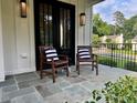 Inviting front porch with bluestone pavers and seating area with stylish chairs and pillows at 6900 Staghorn Ln, Raleigh, NC 27615